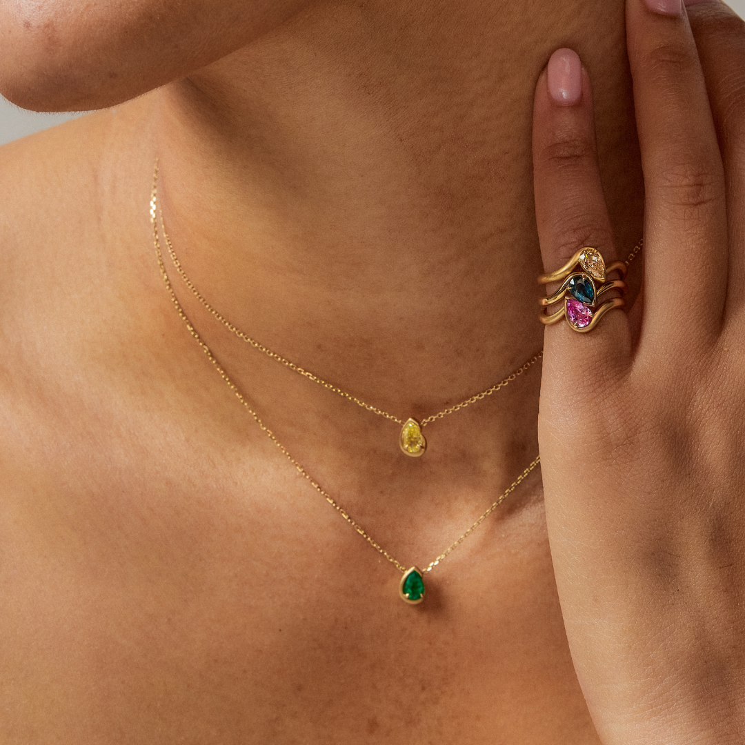 Model wearing BB Thelma pinky ring stack in brown diamond, teal, and pink sapphire. Wearing BB Thelma Necklaces in yellow diamond and green tourmaline.