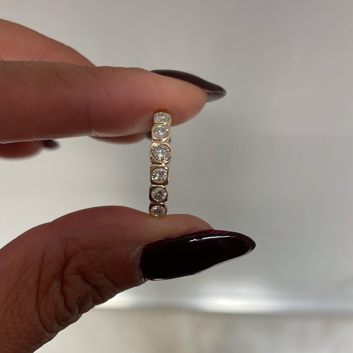 Bezel Set Round Diamond Wedding Band, held between fingers