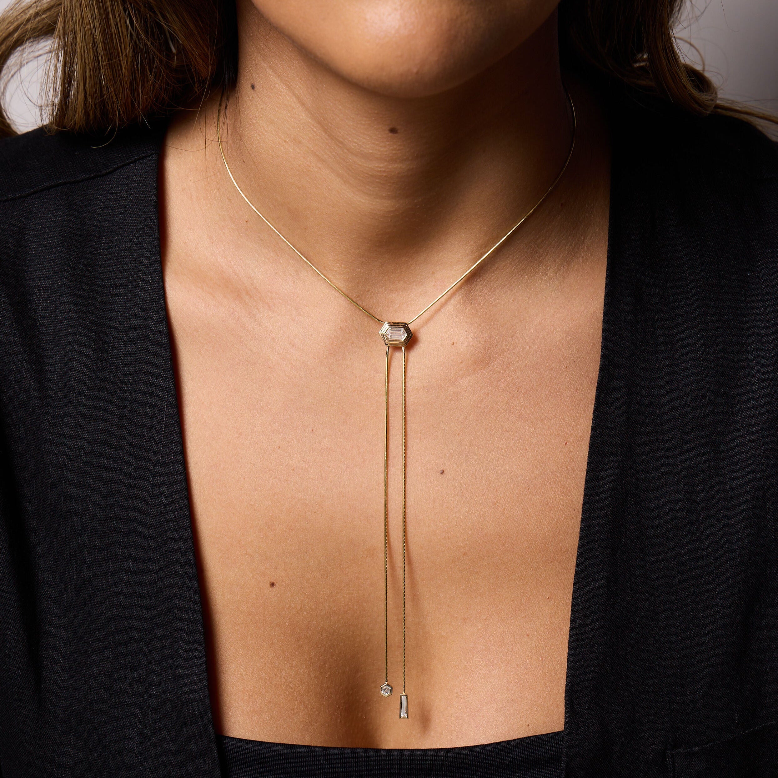 Close-up of a person wearing the Druex Lariat Necklace with bezel-set hexagonal center diamond, hexagonal and tapered baguette accent diamonds.