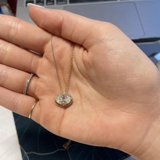 Oval Diamond Necklace in a Pave and Bezel setting, held in hand