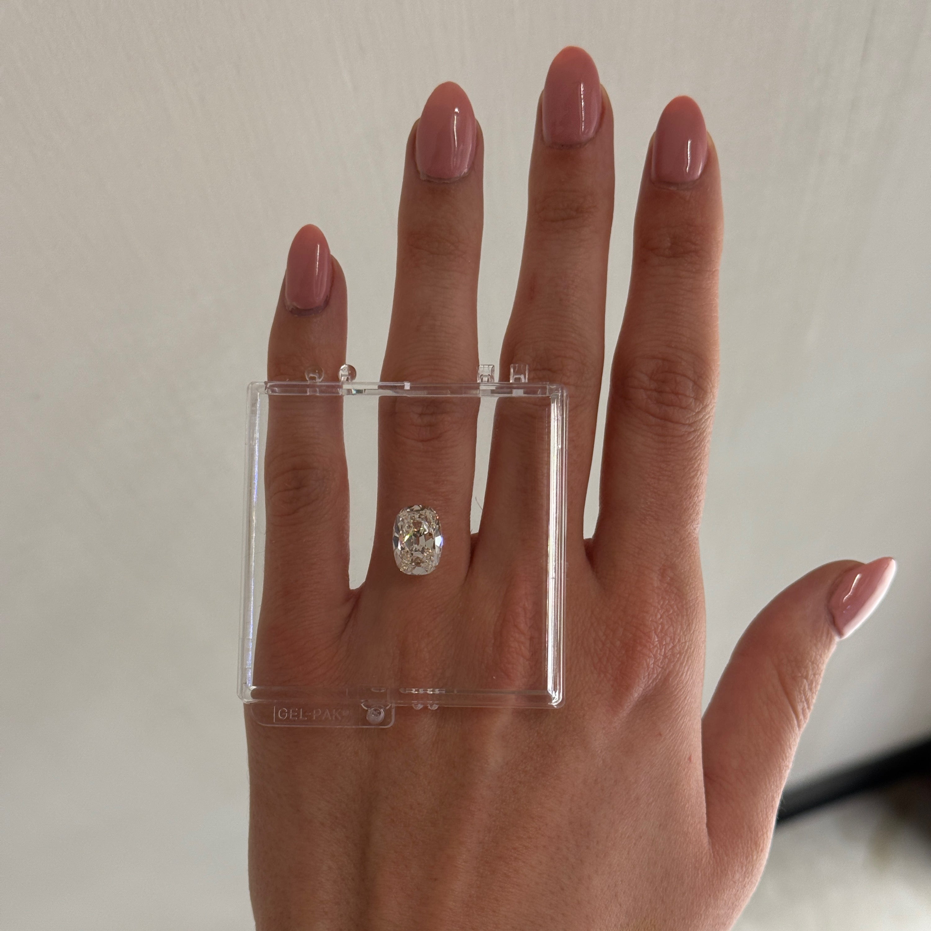 hand with loose 4.01 carat old mine diamond laid over ring finger