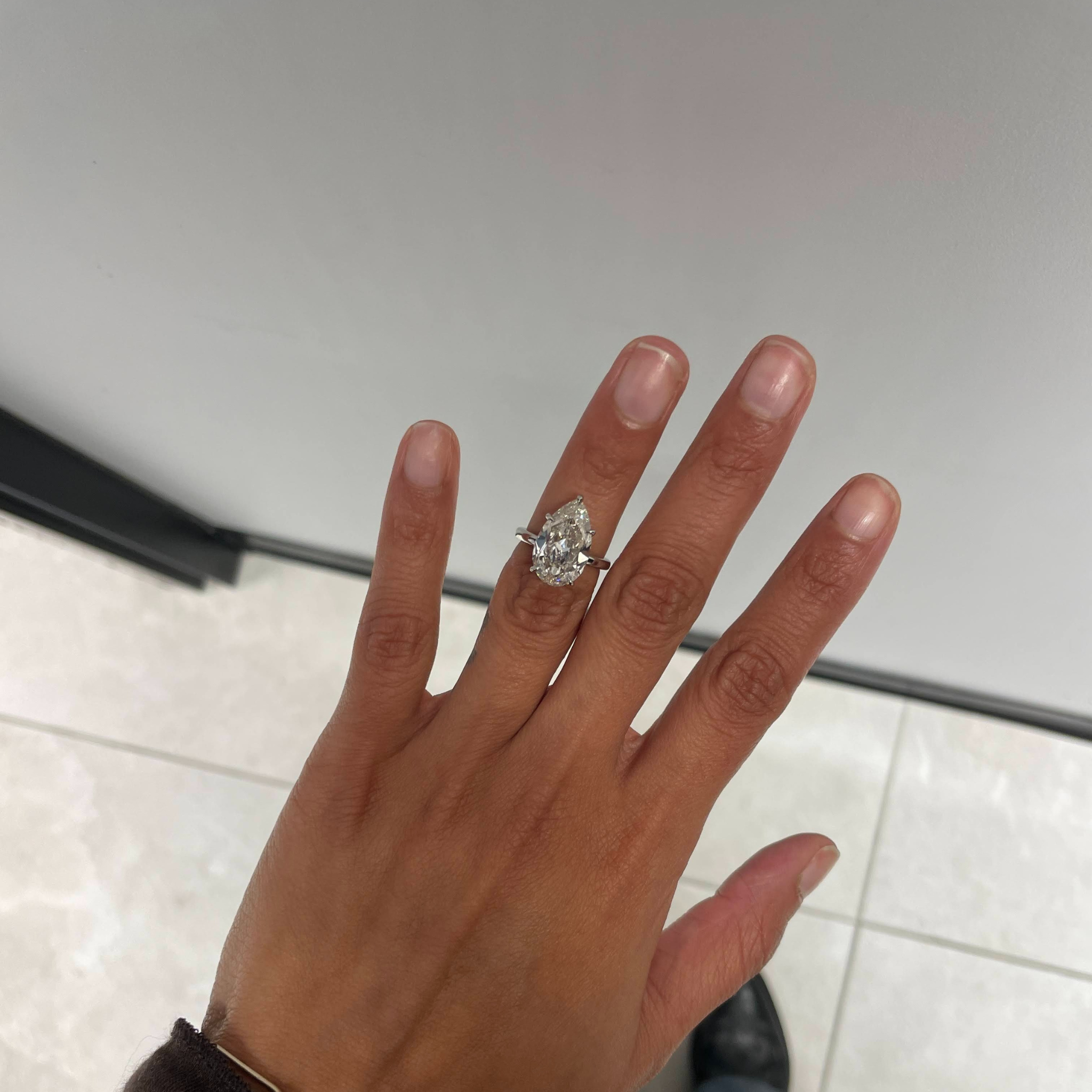 Hand wearing a diamond ring on a neutral background