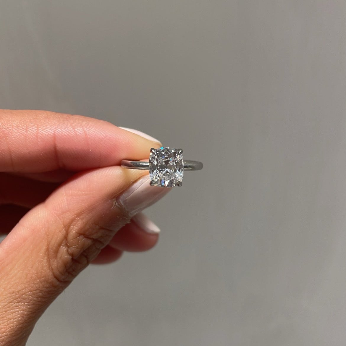 Cushion Cut Diamond Solitaire Ring, held between fingers