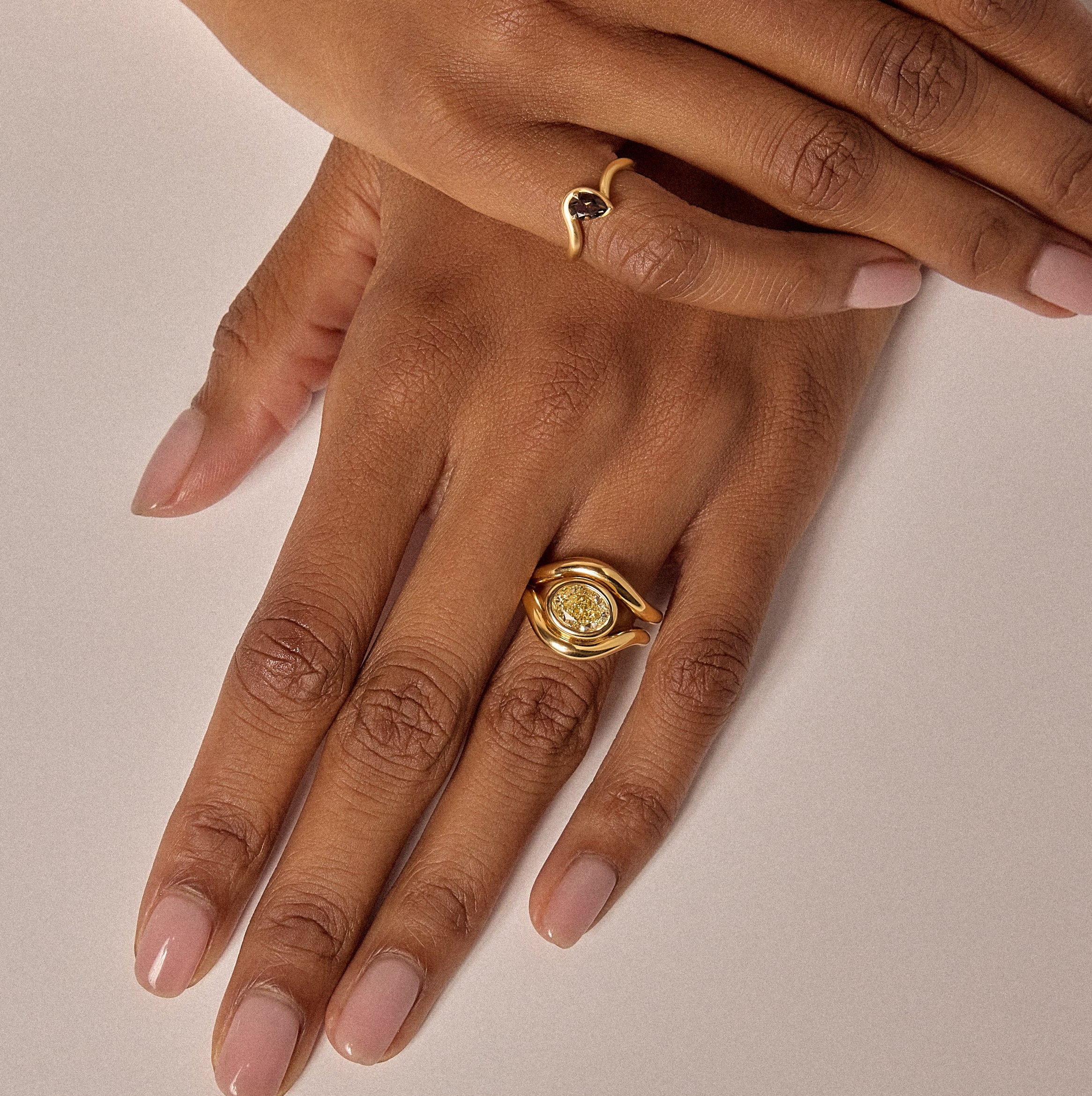 Close-up of hands with gold ring and bracelet on a beige background