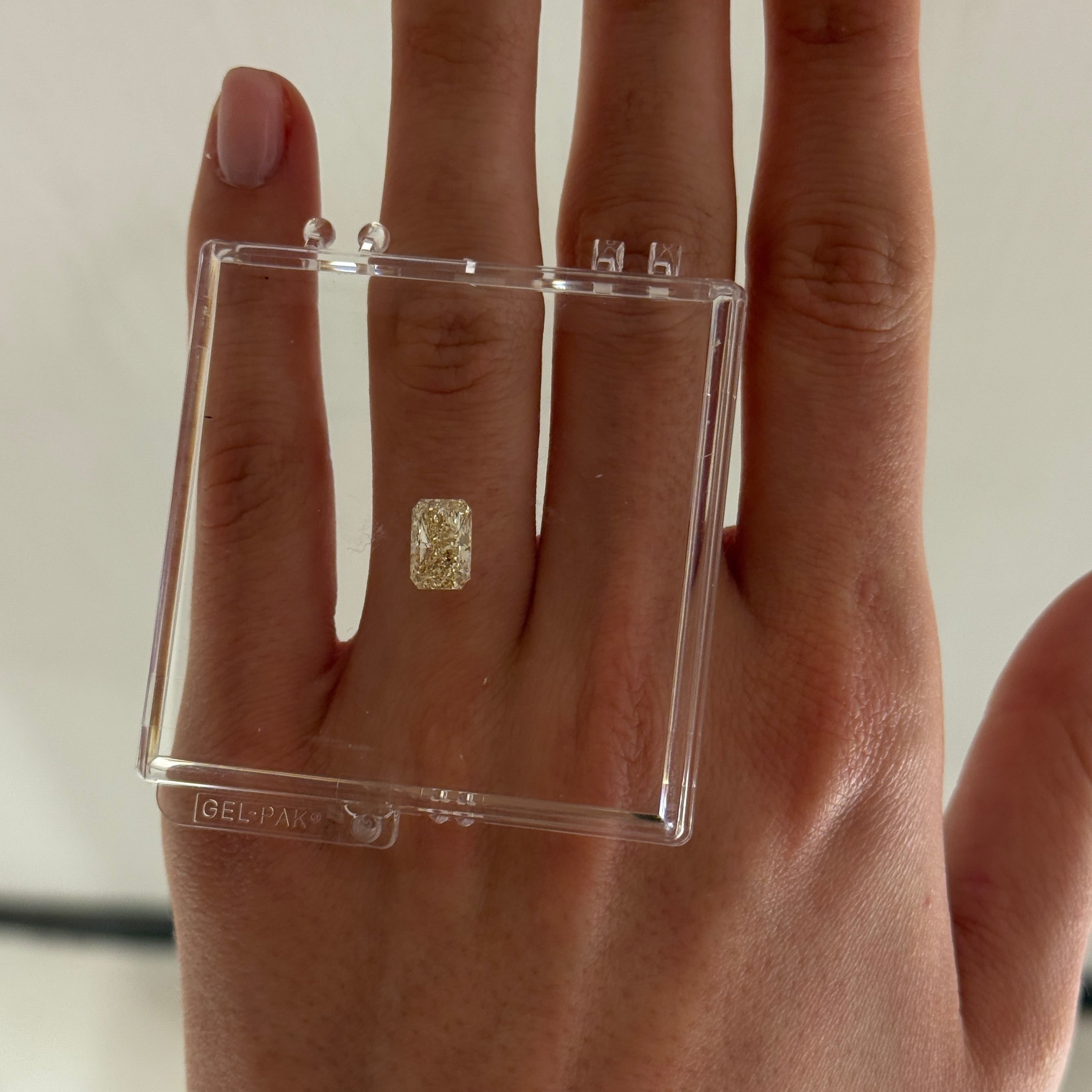 loose yellow radiant cut diamond shown on a hand