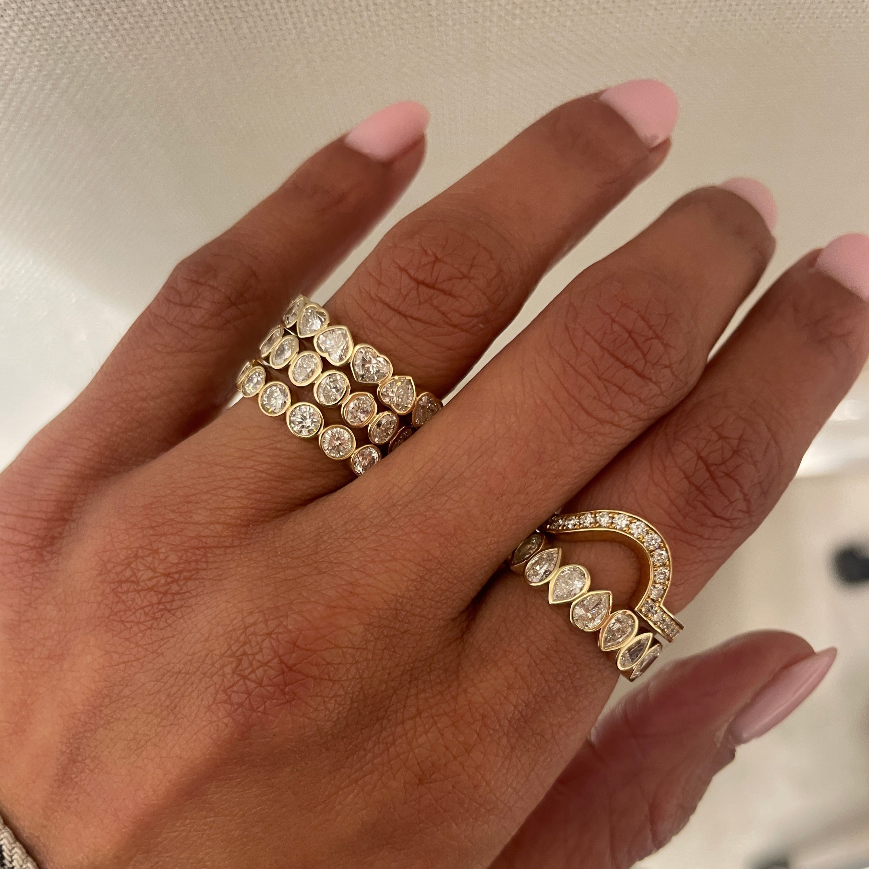 Fortuna round brilliant band on hand with fides heart and flora oval eternity bands  in 18 kt yellow gold. 