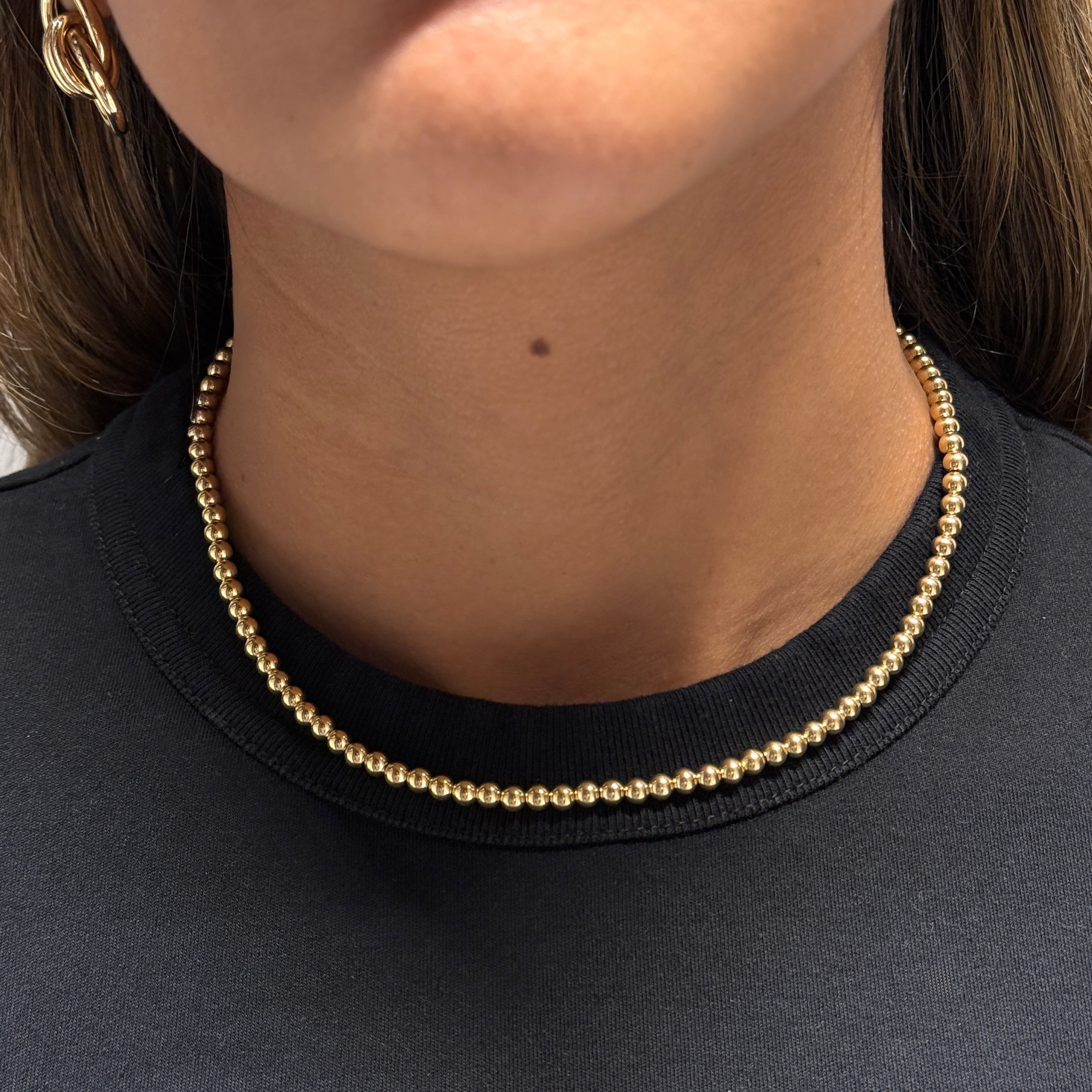 Gold necklace worn by a person against a black shirt