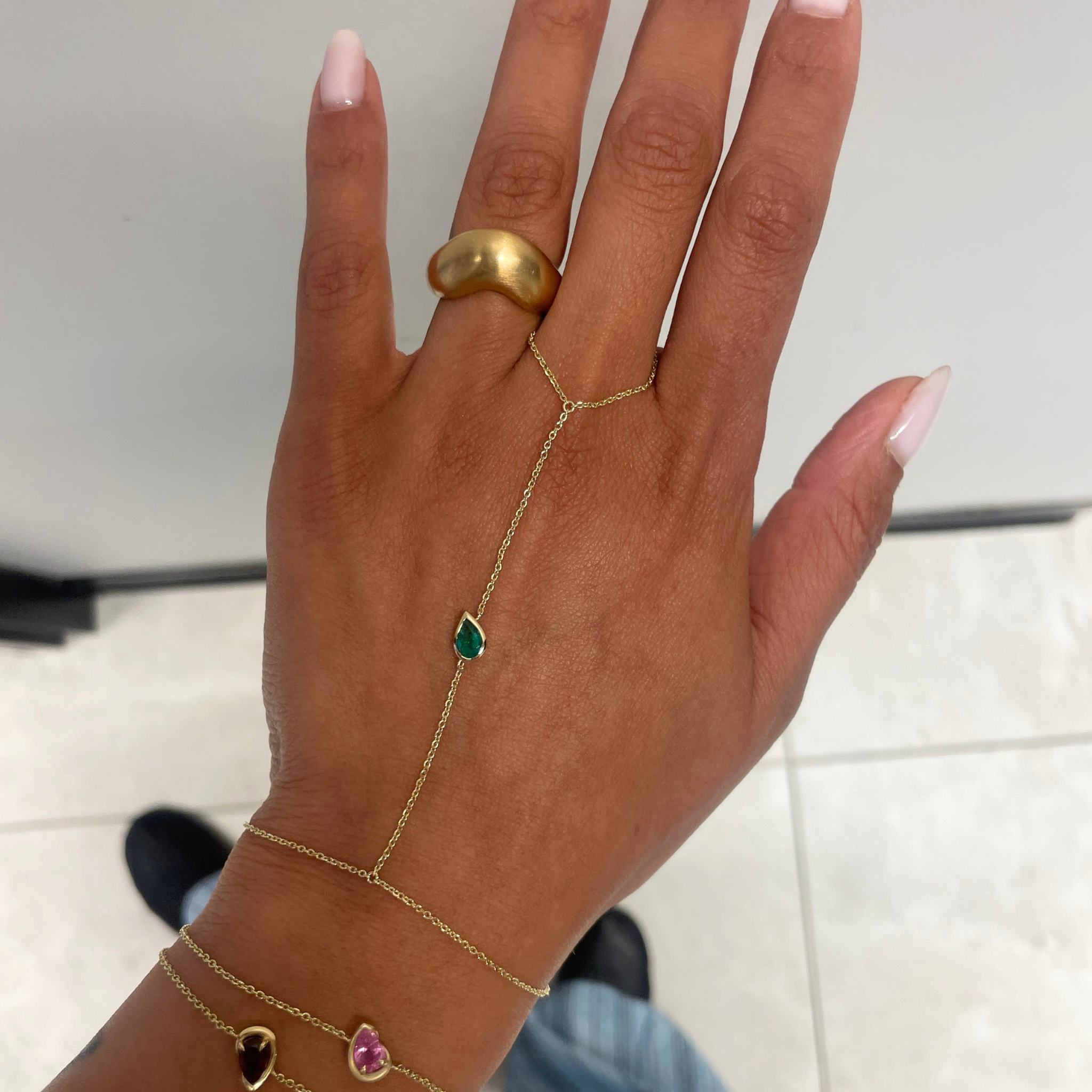 woman's hand spread out showing green hand chain and chunky gold ring