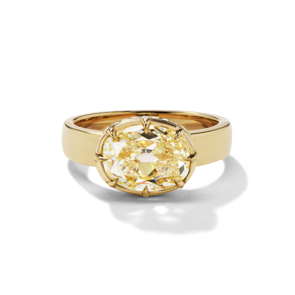 An 18KT yellow gold ring with a large oval yellow diamond centerpiece and a hidden halo of smaller diamonds around it.
