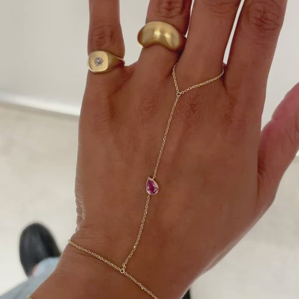 hand moving back and forth in a pink hand chain and gold rings