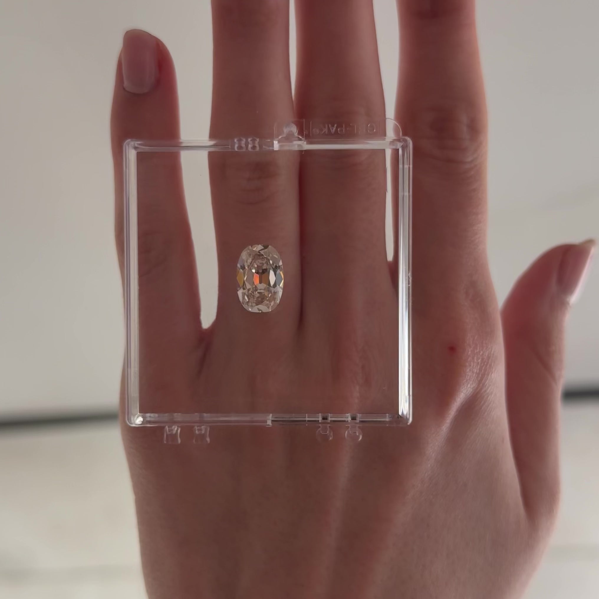 loose cushion brilliant cut diamond on gel box on hand moving back and forth