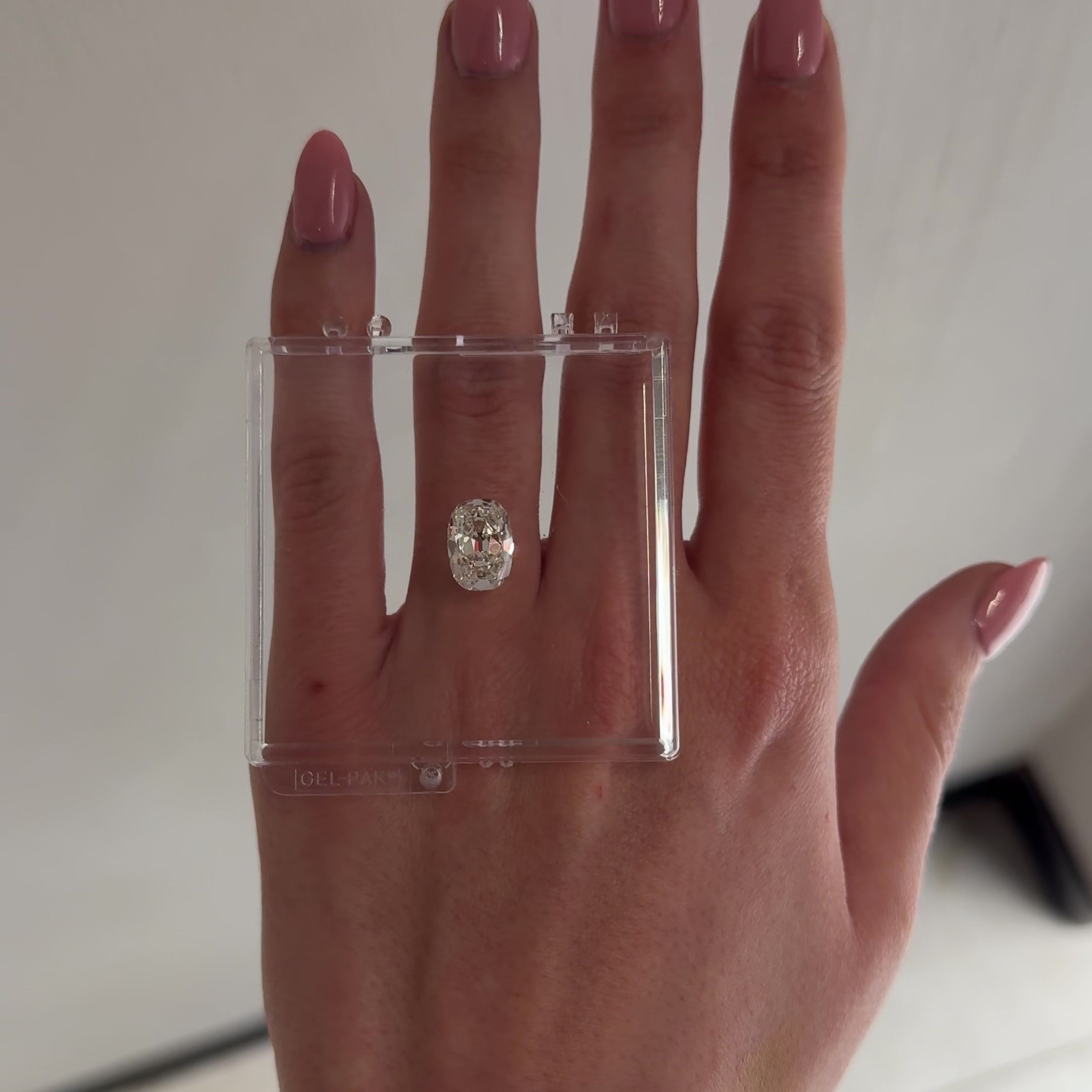 hand with loose diamond laid over ring finger tilting back and forth