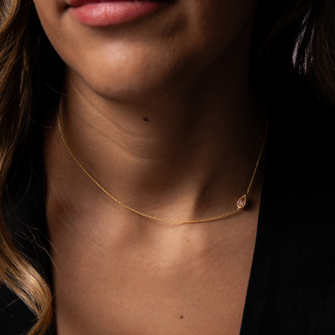 Brown pear cut diamond set on the side of a yellow gold chain necklace