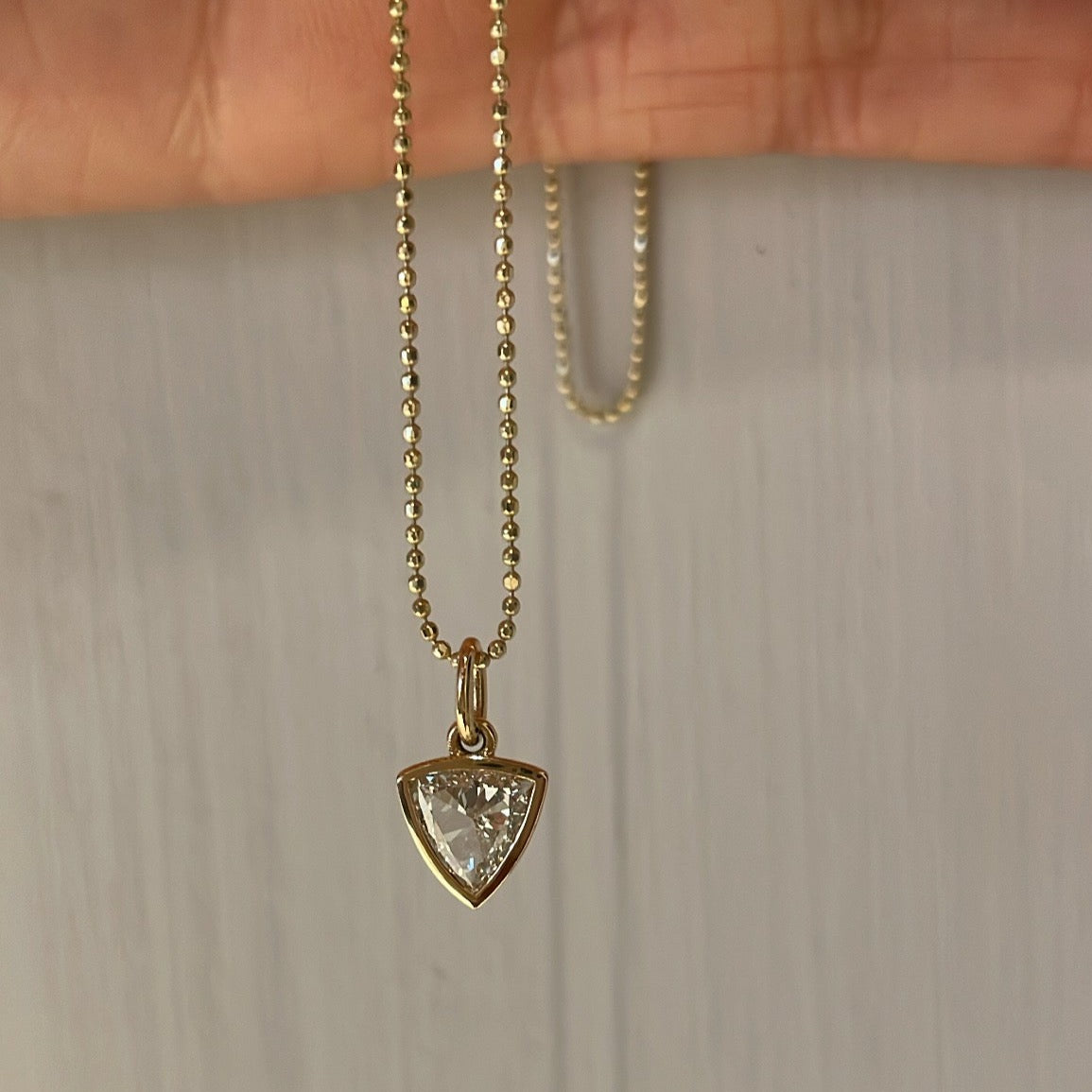 TORI Rosecut Diamond Charm Necklace, held in hand